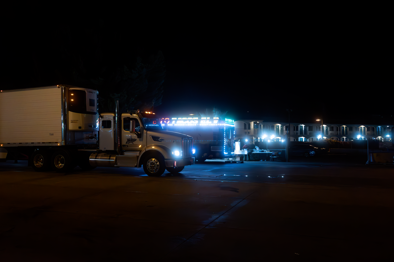 Two brightly lit trucks parked in an urban area at night, showcasing their vibrant lights.